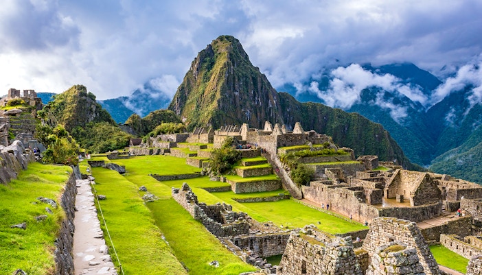 Machu Picchu ruins with terraces and Huayna Picchu mountain in the background.
