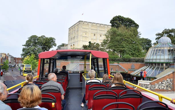Open-top bus tour passing Norwich Castle and Castle Mall.