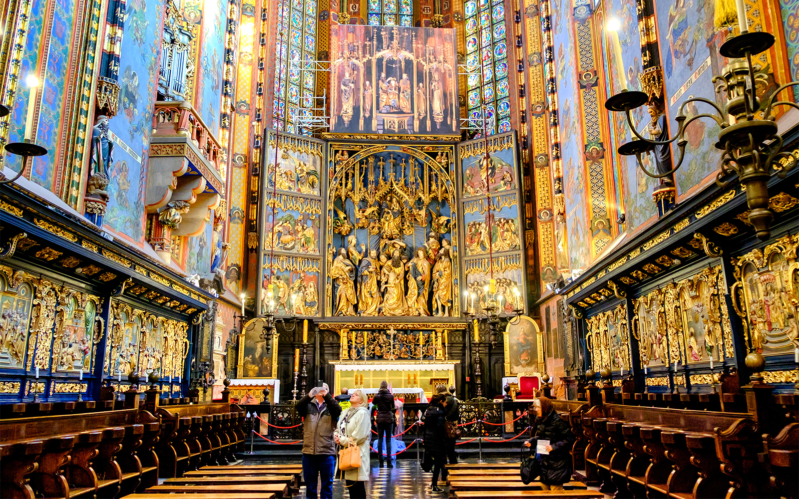 High Altar inside St Mary's Basilica, Krakow, Poland, with intricate wood carvings and colorful stained glass.