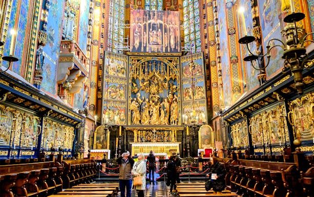 High Altar inside St Mary's Basilica, Krakow, Poland, with intricate wood carvings and colorful stained glass.