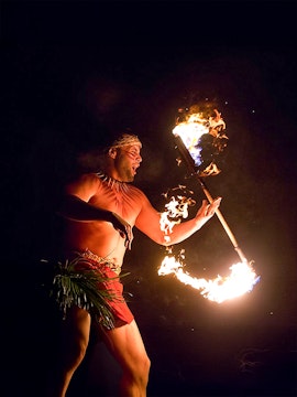 Fire dancer performing with flaming torch at Paradise Cove Luau, Hawaii.