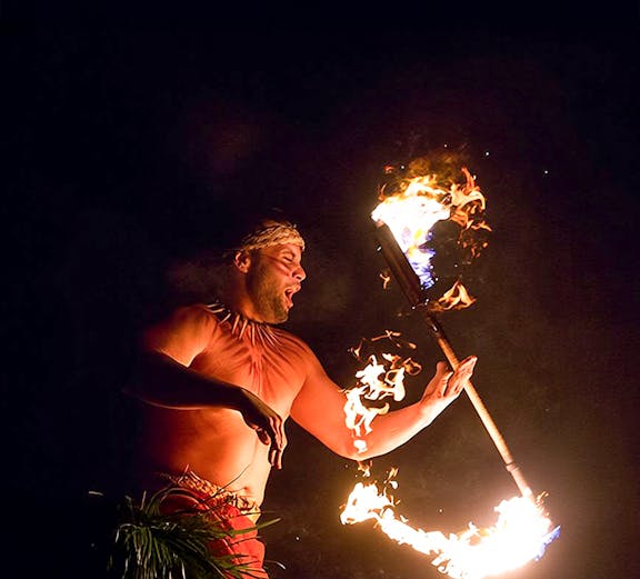 Fire dancer performing with flaming torch at Paradise Cove Luau, Hawaii.