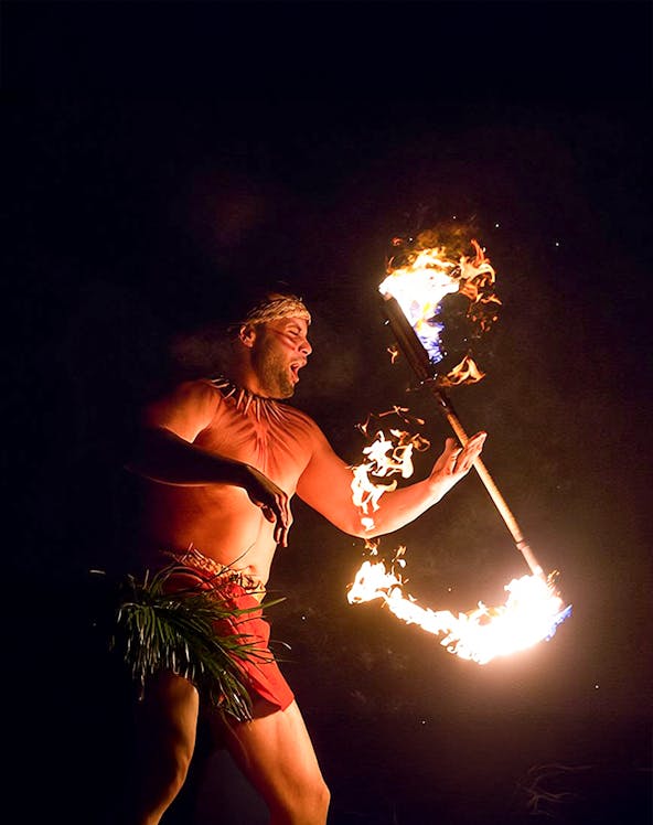Fire dancer performing with flaming torch at Paradise Cove Luau, Hawaii.