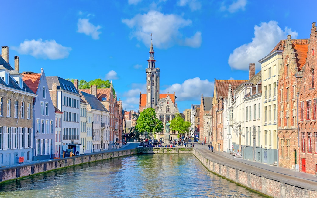 Canal view with historic buildings and Belfry of Bruges in Bruges, Belgium.