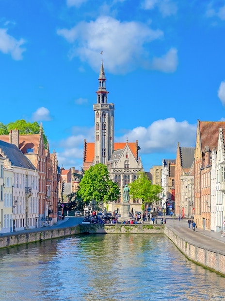 Canal view with historic buildings and Belfry of Bruges in Bruges, Belgium.