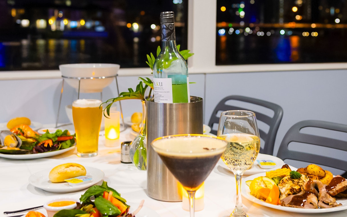 Dinner setting on a Gold Coast sightseeing cruise with wine, cocktails, and gourmet dishes.