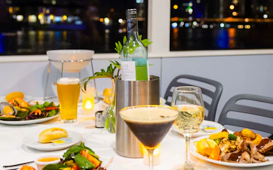 Dinner setting on a Gold Coast sightseeing cruise with wine, cocktails, and gourmet dishes.