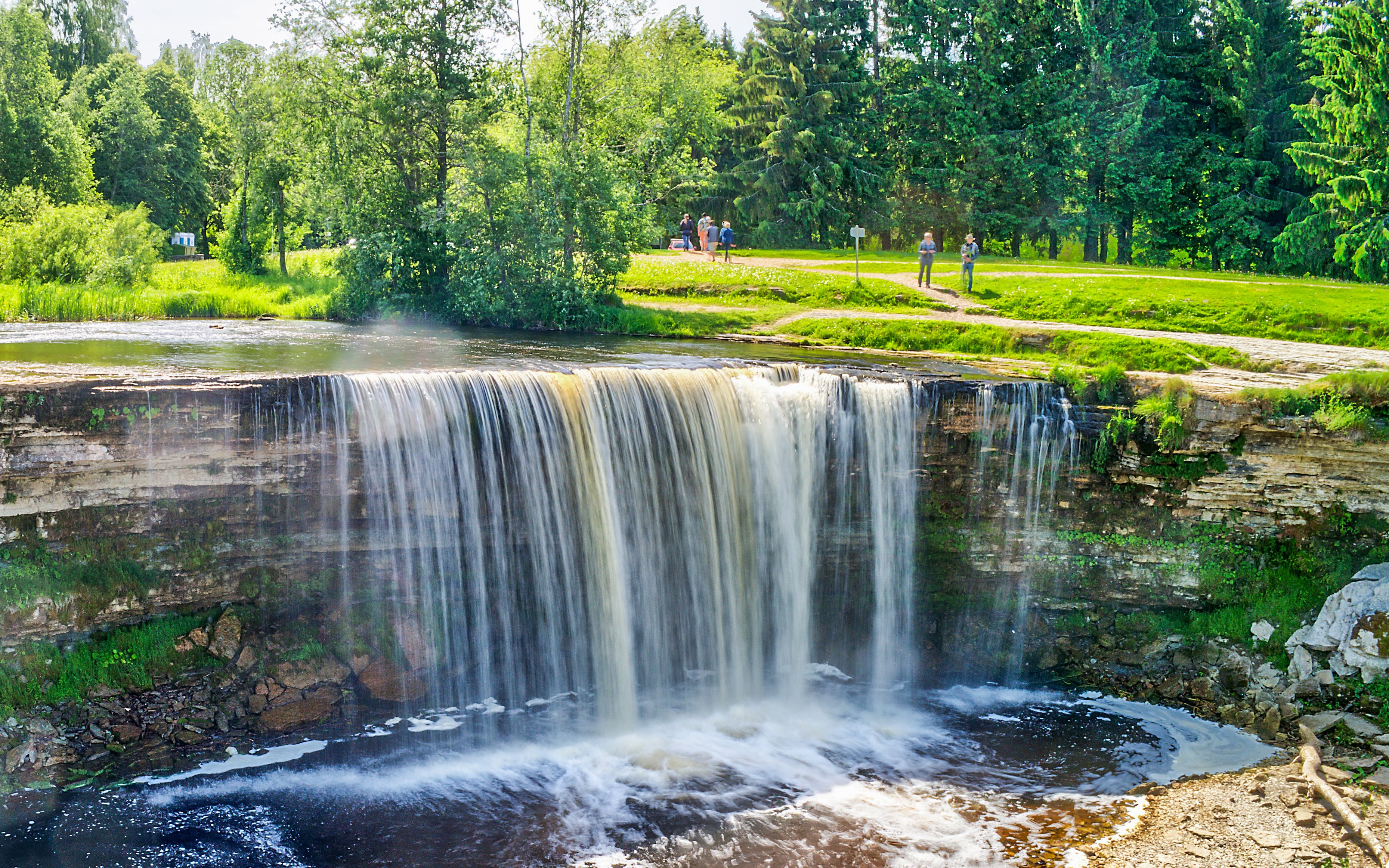 Jagala Waterfall cascading over rocks in a lush green forest, Northern Estonia.