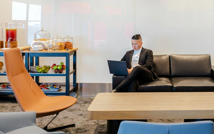 Person using laptop in Plaza Premium Lounge, Terminal 1, Toronto Pearson Airport.