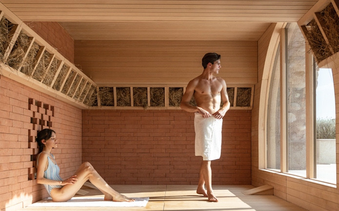 Two people relaxing in a sauna at QC Terme Garda.