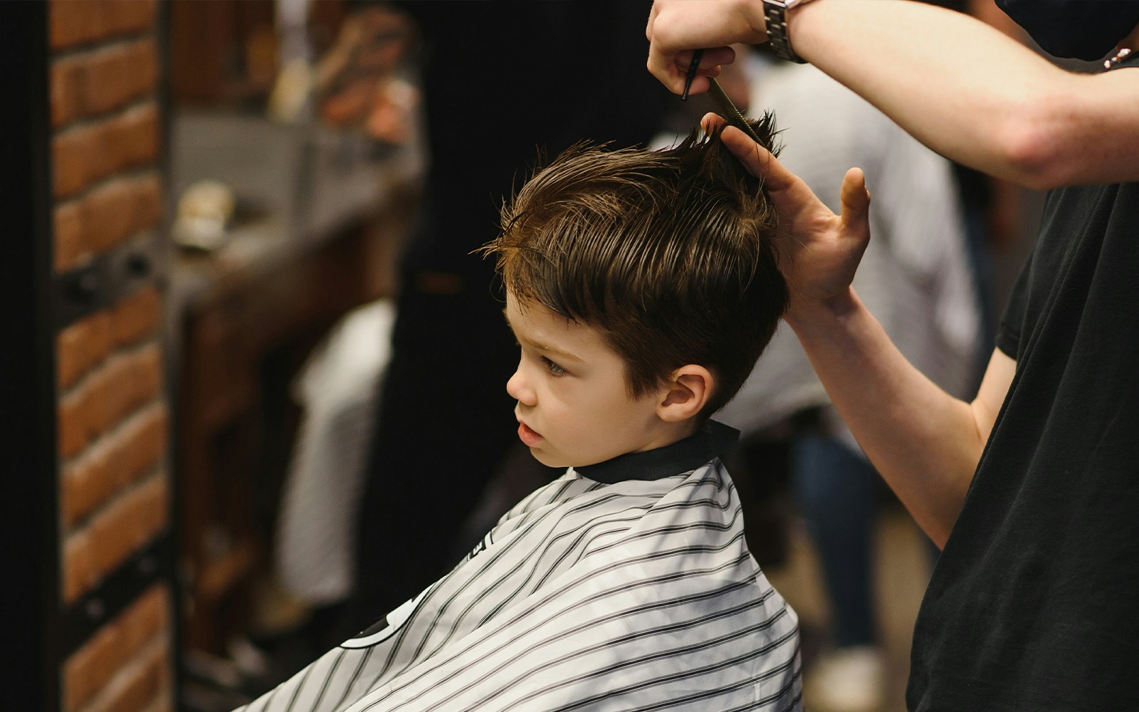 Child getting a haircut at a barbershop.