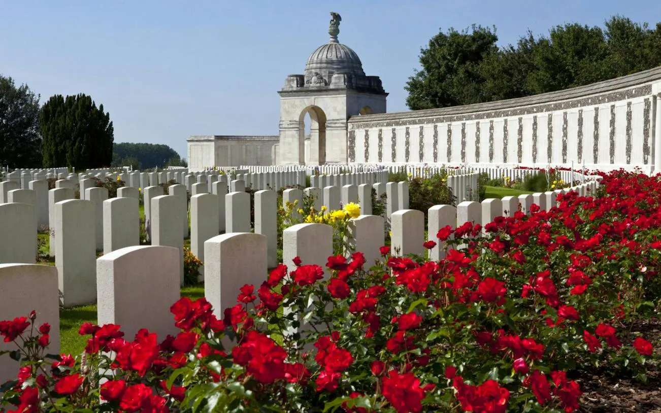 Flanders Fields cemetery with red poppies and Menin Gate memorial, part of WWI tour from Brussels.