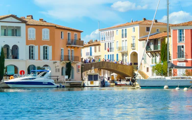 Port Grimaud canal with colorful buildings and boats, part of St Tropez day tour from Nice.