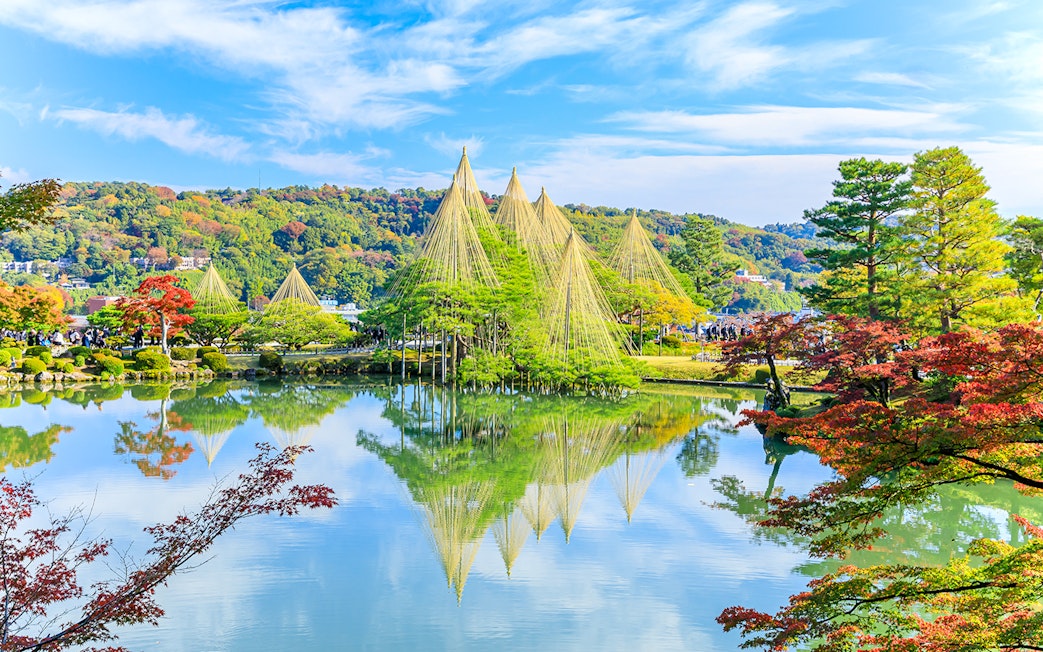 Kenrokuen Garden with traditional yukitsuri ropes over trees and a reflective pond in Kanazawa, Japan.