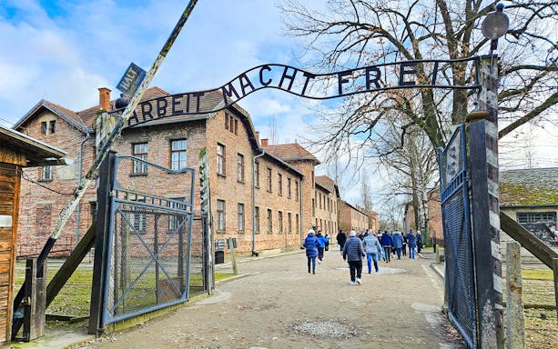 Auschwitz Birkenau entrance gate with visitors walking through, Poland.