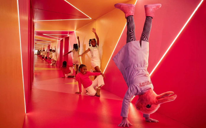 Visitors exploring vibrant, mirrored hallway at Twist Museum with playful reflections.