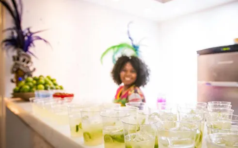 Carnaval Experience in Rio de Janeiro with caipirinhas and a smiling host in costume.