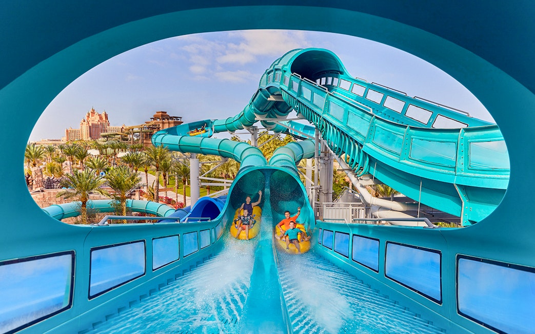 Riders on Medusas Lair water slide at Atlantis, The Palm, Dubai with resort view.