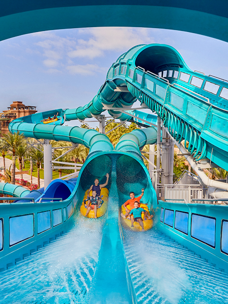 Riders on Medusas Lair water slide at Atlantis, The Palm, Dubai with resort view.
