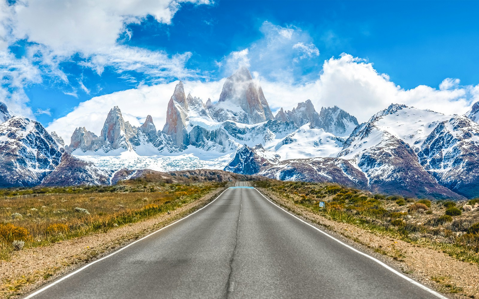 Road leading to Mount Fitz Roy in El Chaltén, Argentina, with snow-capped peaks in the background.