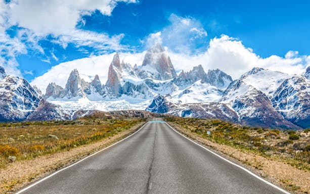 Road leading to Mount Fitz Roy in El Chaltén, Argentina, with snow-capped peaks in the background.