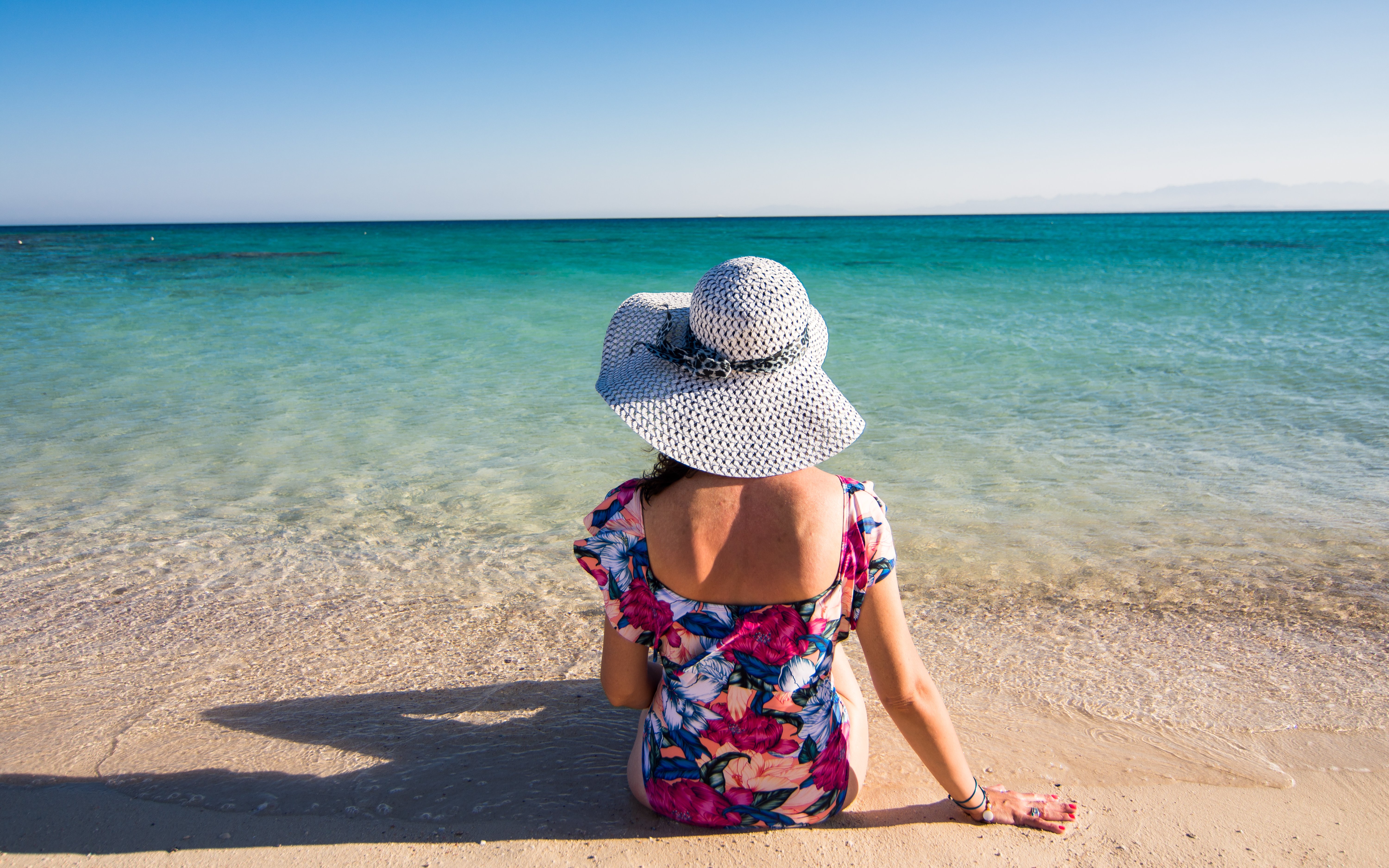 Woman relaxing on Giftun Island beach, Hurghada, facing the sea.