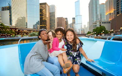 Group enjoying Chicago River cruise with city skyline in background.