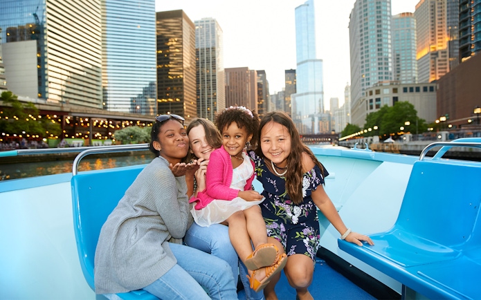Group enjoying Chicago River cruise with city skyline in background.