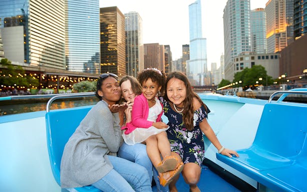 Group enjoying Chicago River cruise with city skyline in background.