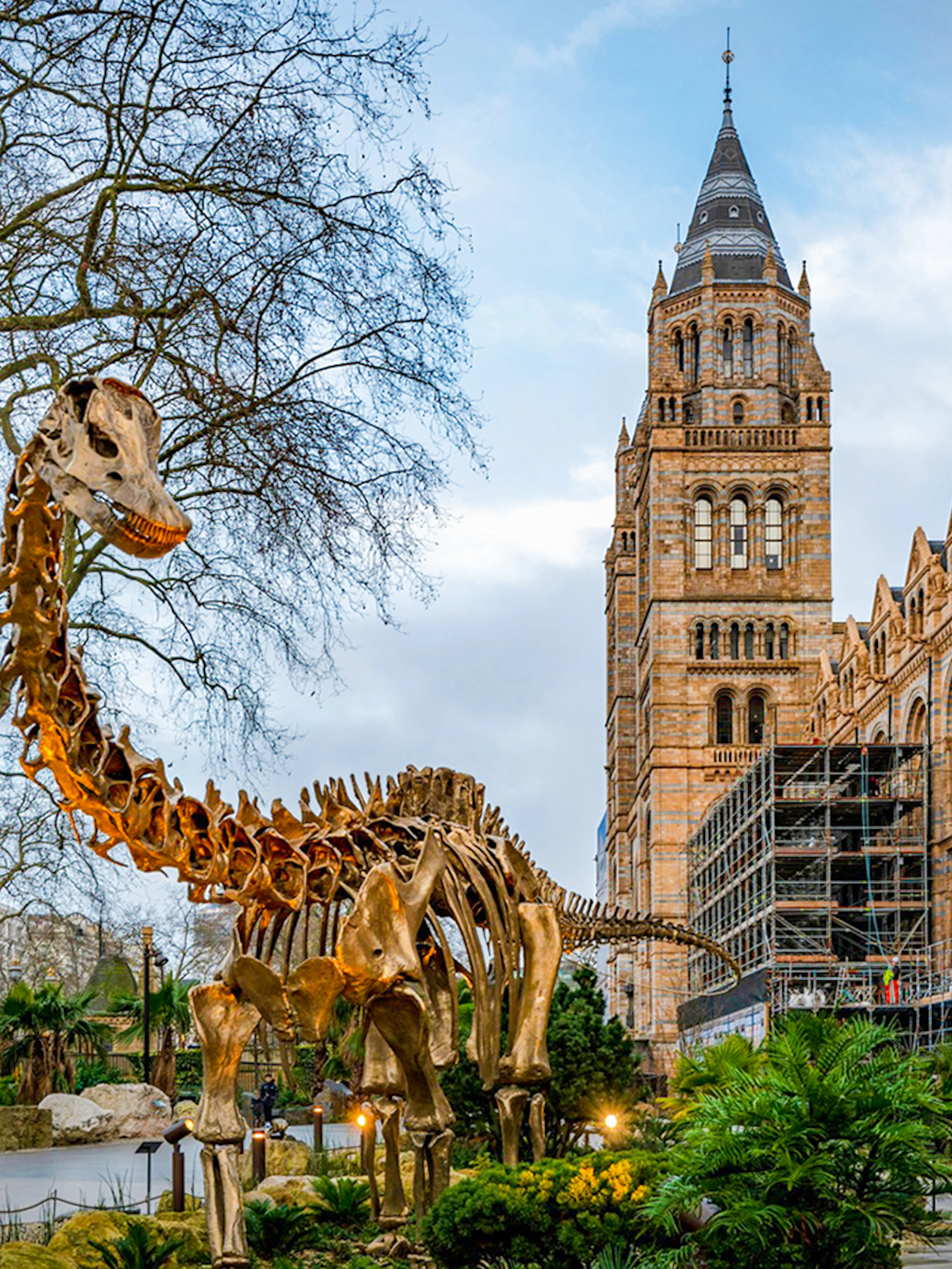 Dinosaur sculpture outside Natural History Museum, London, with historic architecture in the background.