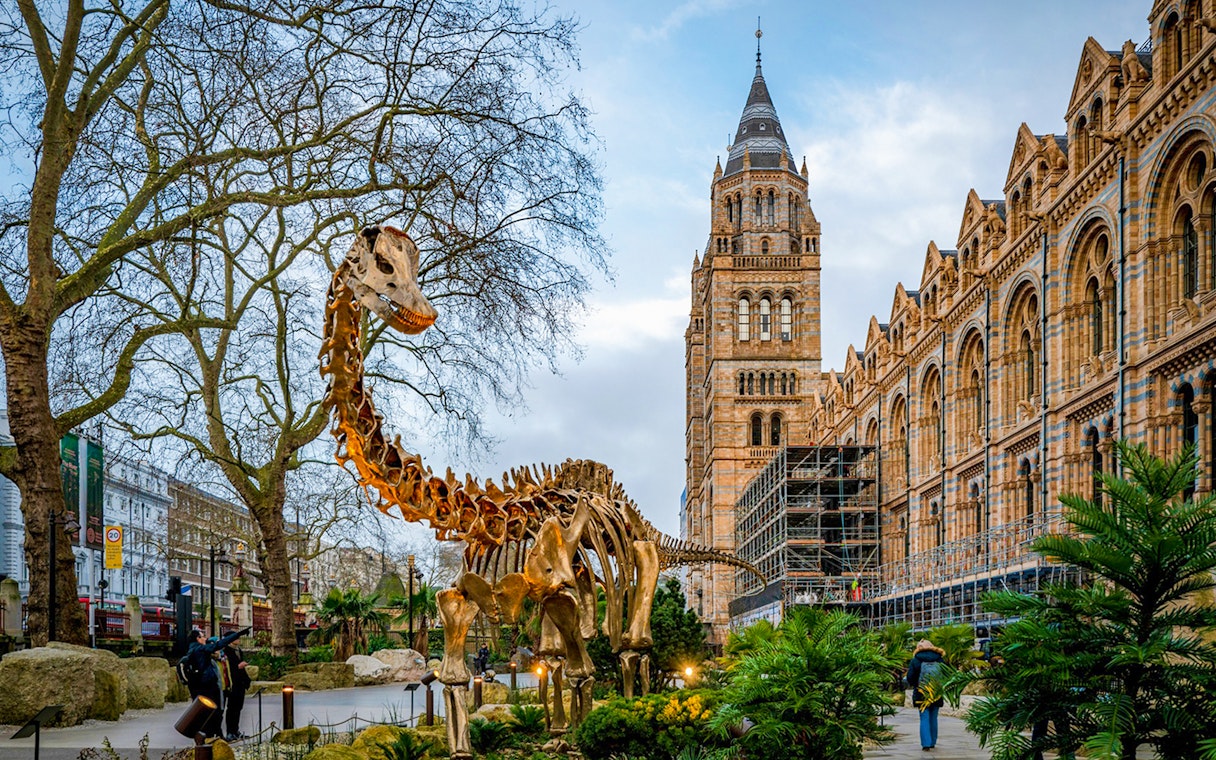 Dinosaur sculpture outside Natural History Museum, London, with historic architecture in the background.