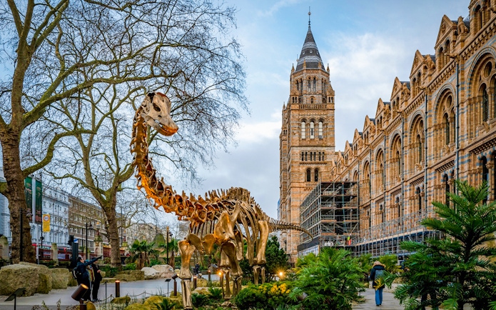 Dinosaur sculpture outside Natural History Museum, London, with historic architecture in the background.