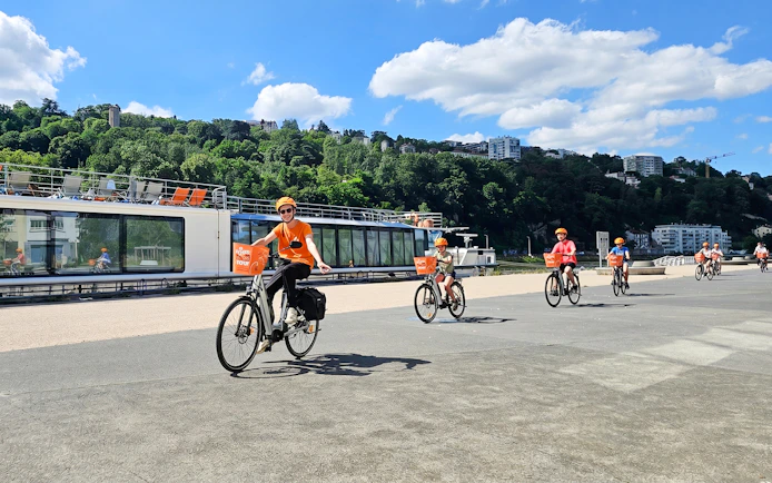 Cyclists on a guided bike tour along the river in Lyon, France.