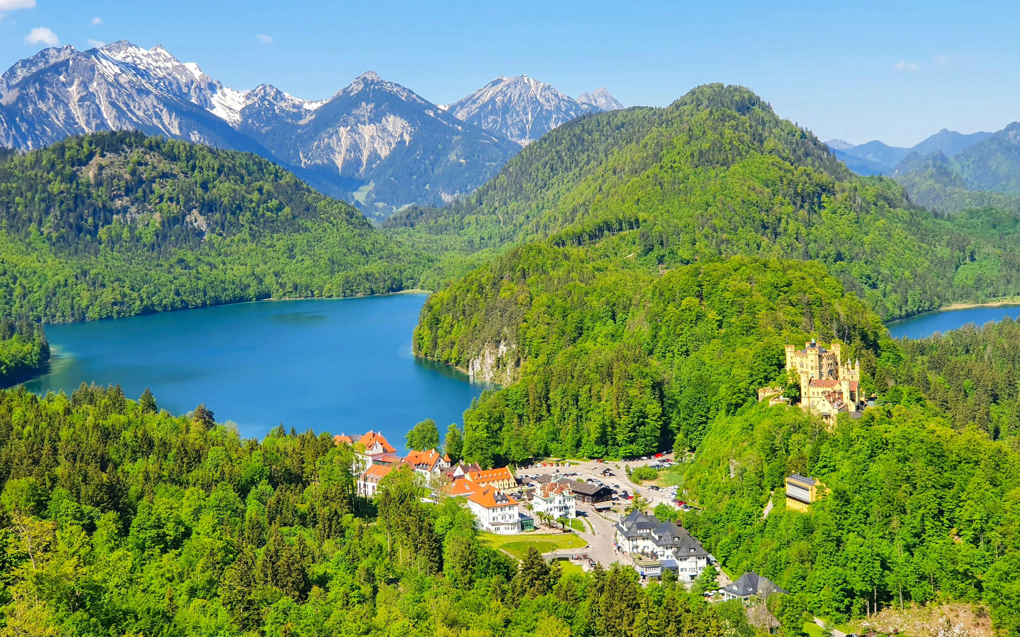 Neuschwanstein and Hohenschwangau Castles surrounded by Bavarian Alps and lake.