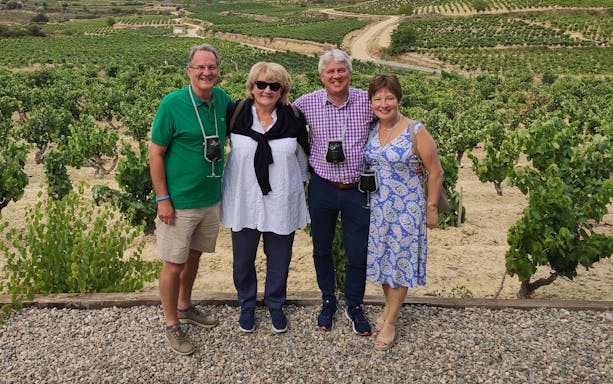 Group enjoying a vineyard tour in Rioja, Spain, with lush grapevines in the background.