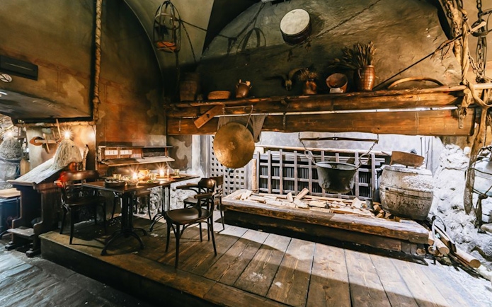 Medieval dining setup with wooden tables, chairs, and rustic decor.