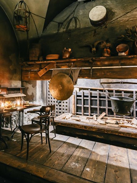 Medieval dining setup with wooden tables, chairs, and rustic decor.