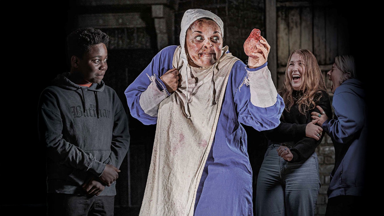 Performer in costume holding a prop heart at London Dungeon VIP experience.