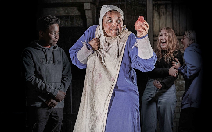 Performer in costume holding a prop heart at London Dungeon VIP experience.