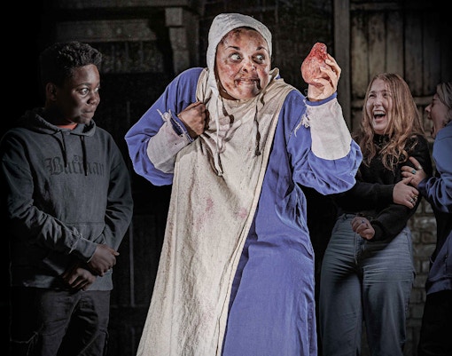 Performer in costume holding a prop heart at London Dungeon VIP experience.
