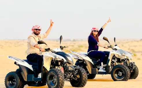 Quad bike riders in Abu Dhabi desert during safari tour.