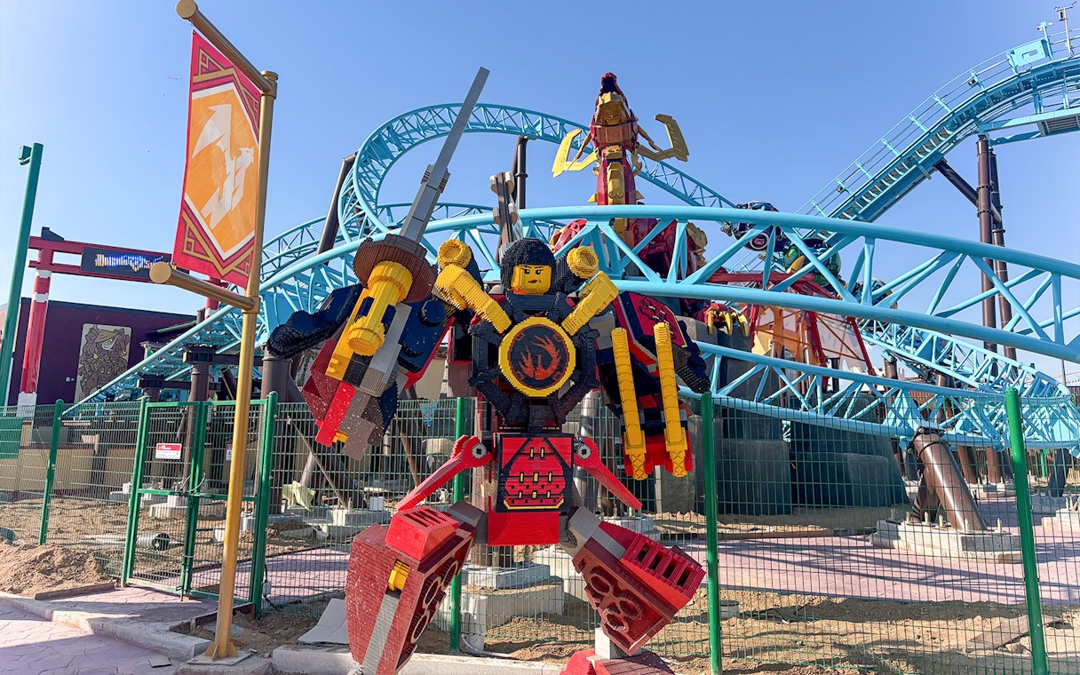 Lego samurai statue in front of roller coaster at Legoland.