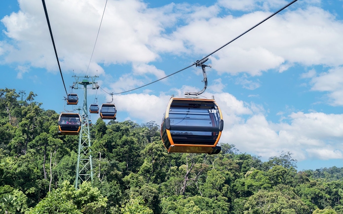 Cable cars ascending to Ba Na Hills over lush green forest.