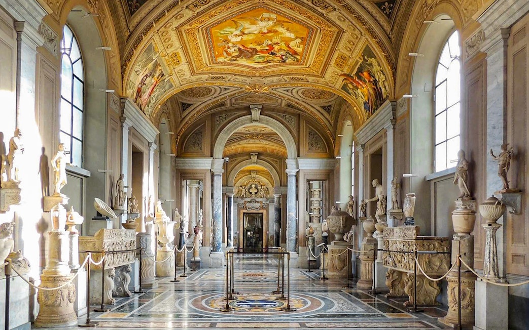 Vatican Museum Gallery with sculptures and ornate ceiling.