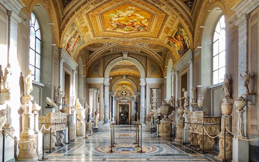 Vatican Museum Gallery with sculptures and ornate ceiling.