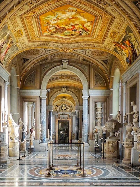 Vatican Museum Gallery with sculptures and ornate ceiling.