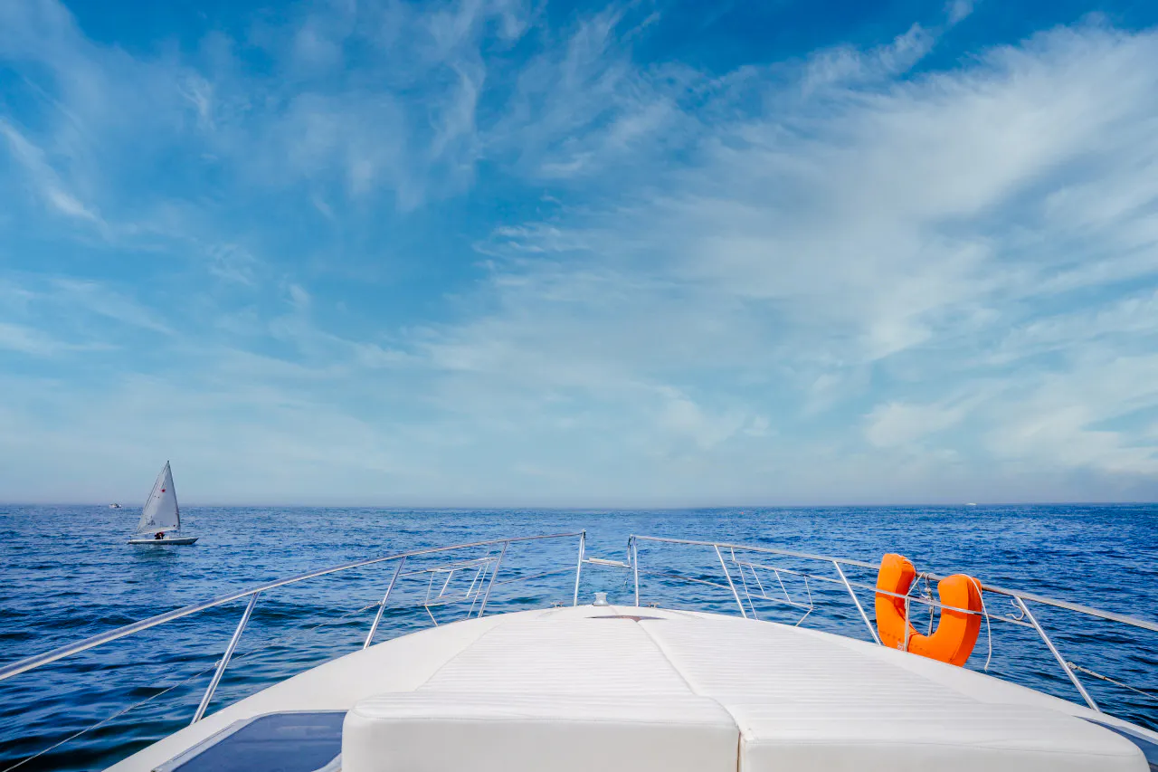 Boat deck view with life preserver, sailboat in distance, Agadir fishing and swimming trip.