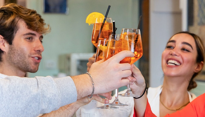 People clinking wine glasses during a cooking class in Rome.