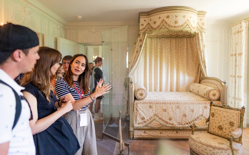 Guide explaining the private chambers of Marie Antoinette at the Palace of Versailles to a tour group.