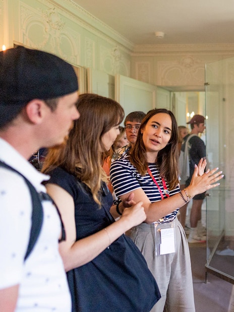 Guide explaining the private chambers of Marie Antoinette at the Palace of Versailles to a tour group.
